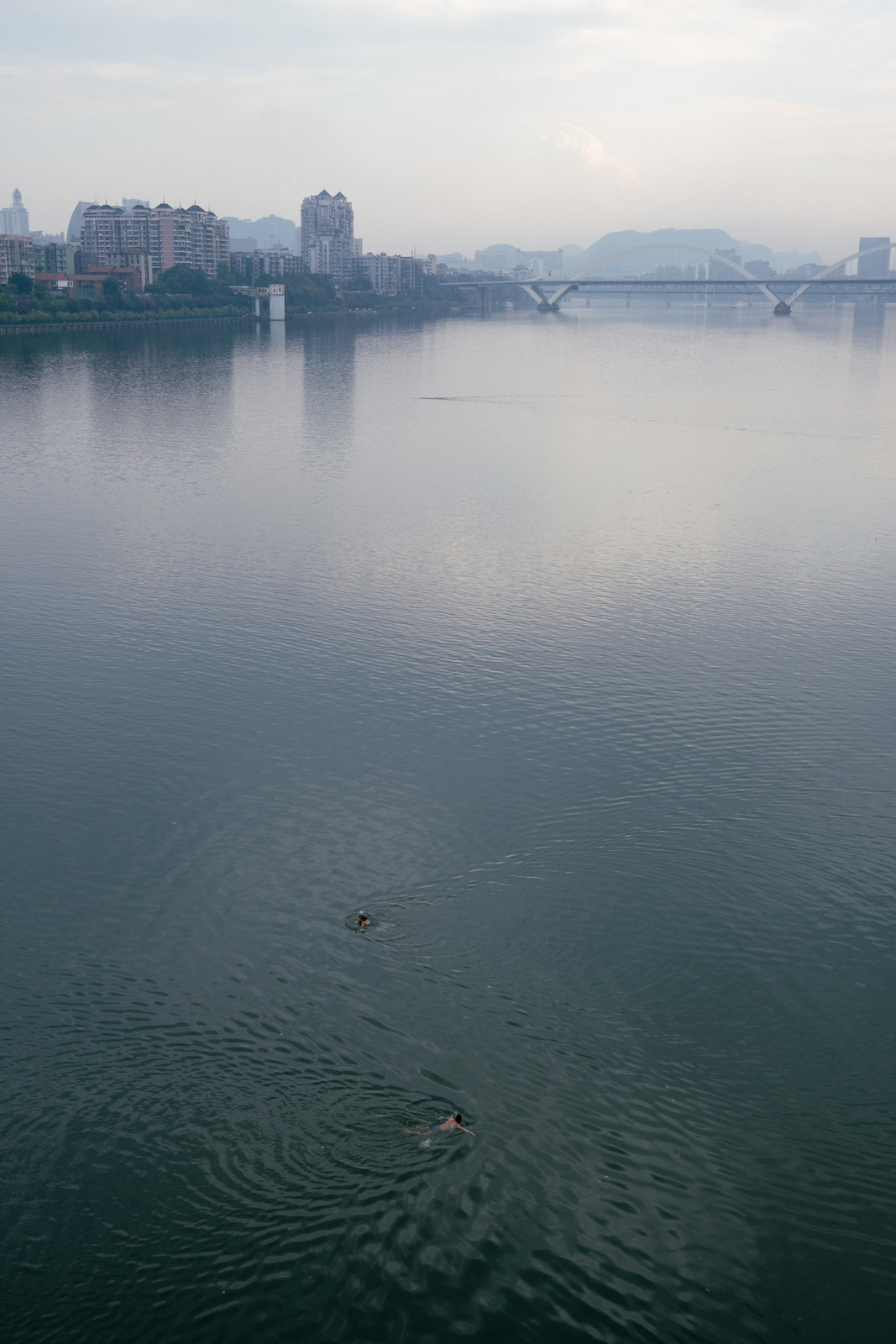 Two people swimming together in big river in Liuzhou